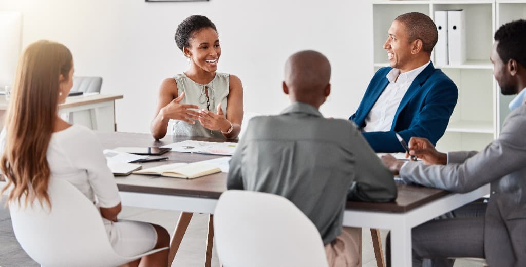 A diverse group of professionals collaborating and discussing around a conference table in a bright, modern office